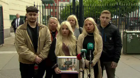 Tony Browne's family outside court on Wednesday - his daughter holds a picture of her dad with his three children 