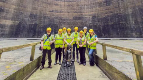 Pat Brundell Group of people wearing hi-vis with a cooling tower