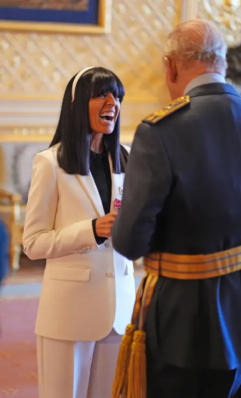 PA Claudia Winkleman smiling while talking to King Charles III