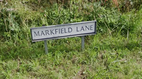 Google A street sign saying Markfield Lane with grass around the sign

