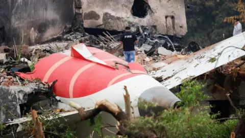 EPA Part of a jet engine lies on the floor with a firefighter standing on top of the rubble