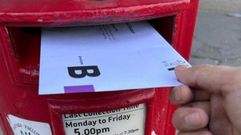 A vote being cast via a postbox 