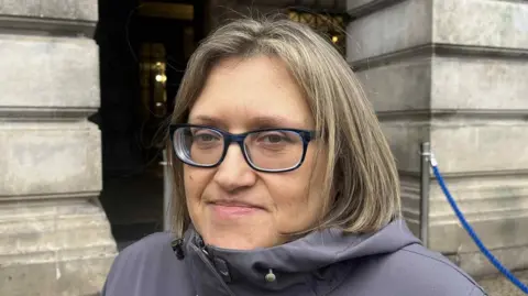 A close-up photo of a woman wearing glasses. 