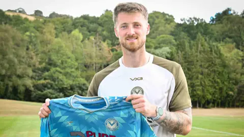 Jake Turner holding a Newport County shirt