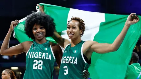 AFP Nigeria's Blessing Ejiofor (L) and Pallas Kunaiyi-Akpanah (R) celebrate with their country's national flag after a Nigerian basketball victory at the Paris 2024 Olympic Games  - 4 August 2024