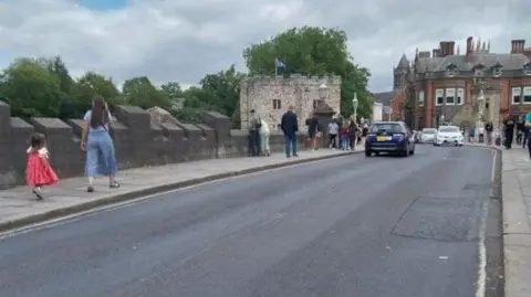 Cars pass and people walk over York's Lendal Bridge, which has a patchy tarmac surface.