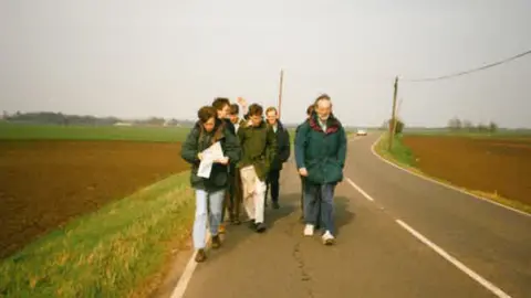 Colin Bell A photo taken in the 1990s of a group walking in the road surrounded by fields either side