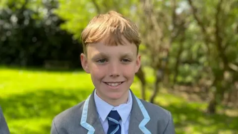 BBC/Kate Bradbrook Henry - boy with short brown hair wearing a grey uniform