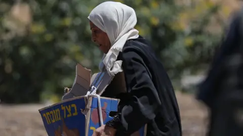 A woman carries a torn box of aid supplies in Gaza. 