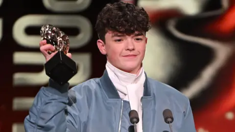 Getty Images Owen Cooper holding up his Bafta award