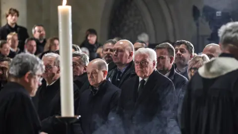 Getty Images Clergy walk past German Chancellor Olaf Scholz (SPD) (CL) and German President Frank-Walter Steinmeier (CR) during a prayer service at Magdeburg Dom