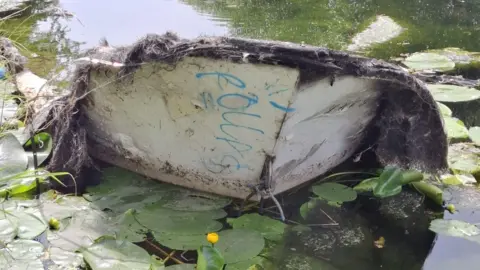 Erewash Canal Association Rotted boat covered in moss upturned in canal
