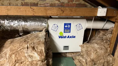Catherine Katzka A ventilation system in a loft. Pipes are seen on each side, and insulation is in the loft as well. 