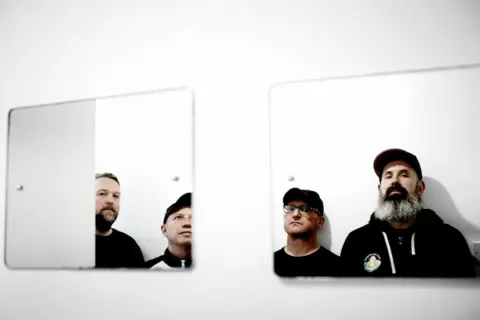 The black Steve Gullick Mogwai reflected in a pair of rectangular mirrors reflected at a pair of rectangular mirrors