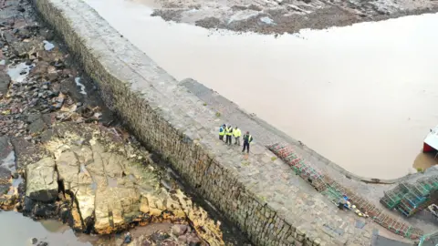 St Andrews Harbour Trust A drone shot of the pier with people in hi-vis tops standing on it