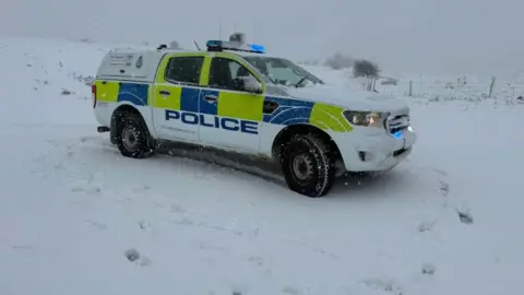 North Yorkshire Police A 4x4 police car parked in snowy fields with blue lights on