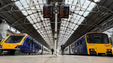 Network Rail two trains on platforms under the glass roof at Manchester Piccadilly