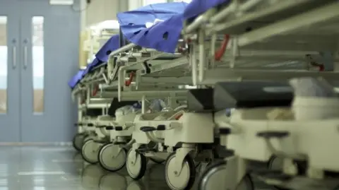 Getty Images A stock image of a hospital corridor with gurneys and bed trolleys