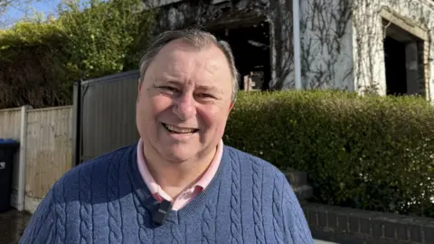 Jeffrey Harrison-Turner smiles for the camera outside a garden