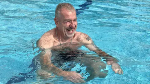 A man smiling in a swimming pool.