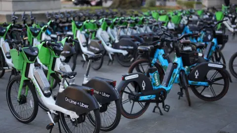Several rows of bikes standing on a London street. 