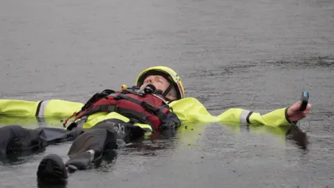 A person in a yellow dry suit float on the top of the lake