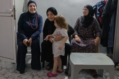 Three women and a young girl sit inside a safe room.