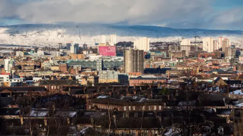A view of Glasgow and its skyline during a winter's day, with snow on the hills behind the city centre