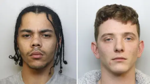 Bailey Westcott, wearing a grey tracksuit. He has brown dreadlocked hair. Jamie Ogbourne, wearing a grey hoodie. He has short brown hair.