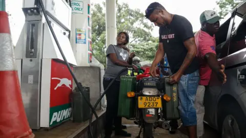 AFP A petrol attendant serves a motorcyclist with two jerry cans attached to his motorbike at a fuel station,