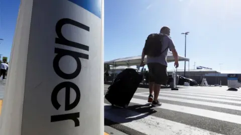 Reuters A person with suitcase by an Uber sign