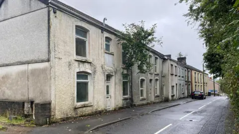 Lewis Smith Homes in Cyfyng Road, and a tree appearing to grow out of the upstairs window of one property