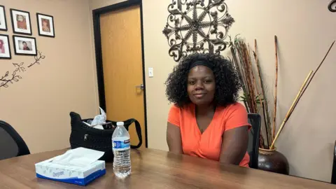 Dominic Richmond, una mujer que viste una camiseta naranja, se sienta en las oficinas de Children's Cabinet, una organización sin fines de lucro en el área de Las Vegas. 