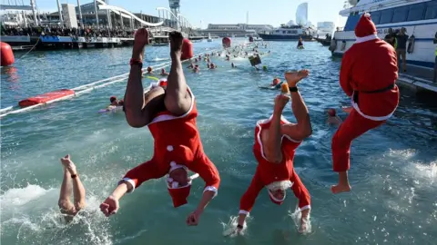 AFP Participants in a Santa Claus costume jump into the water during the 110th edition of the "Copa Nadal" (Christmas Cup)