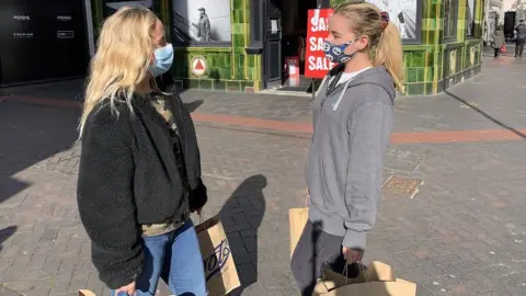 Two women wearing masks and shopping