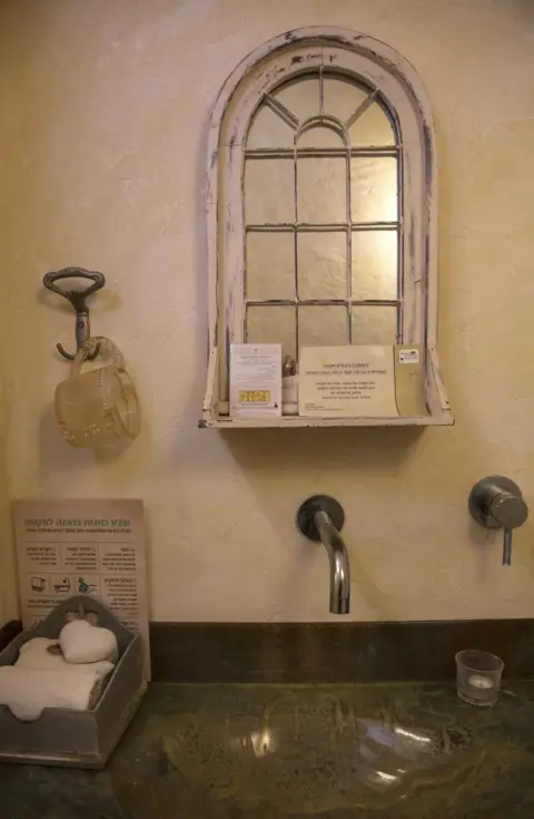 Heidi Levine A poster encouraging women to examine themselves for breast cancer is seen in a changing room at a Mikveh outside of Jerusalem. (Photo by Heidi Levine for The BBC).