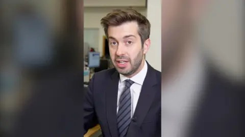 BBC Correspondent Joe Pike wearing suit, shirt and tie