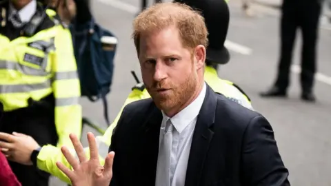 PA Media Prince Harry waving to reporters as he arrives at court