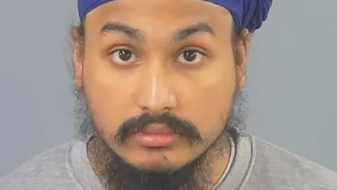 Police handout Custody photo of Vickrum Digwa, a man with a beard, a grey jumper and a purple turban looking to the camera.