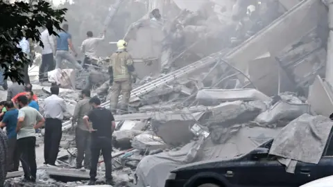 Getty People look over damage to buildings in Nobonyad Square following Israeli air strikes