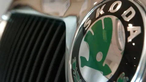 Getty Images Close-up shot of a green and Skoda badge on the front grill of a car. 