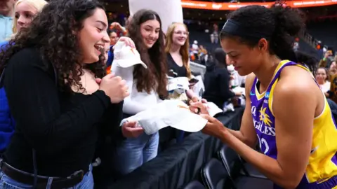 Getty Images Rae Burrell #12 of the Los Angeles Sparks signs fan gear after the game on May 4, 2024 at Rodgers Place in Edmonton, Canada. NOTE TO USER: User expressly acknowledges and agrees that, by downloading and/or using this Photograph, user is consenting to the terms and conditions of the Getty Images License Agreement.