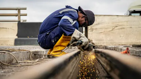 BBC/Ayo Bello A welder on the Third Mainland Bridge, Lagos, Nigeria