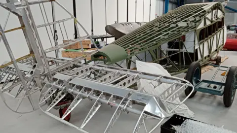 Medway Aircraft Preservation Society Limited The shell of an aeroplane as it is being restored in a hangar