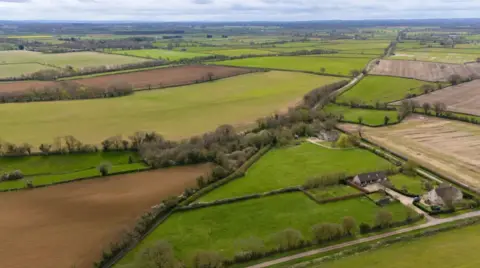 PA Media Aerial image showing several fields and rural roads, with a handful of houses scattered among the countryside scene.