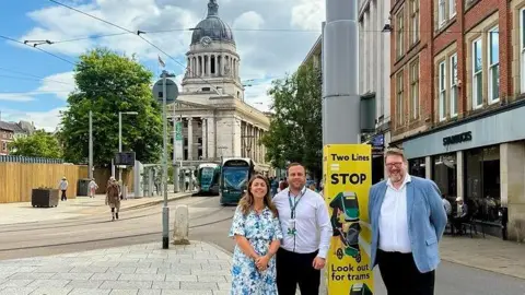 People posing with a sign around a lamppost near Old Market Square