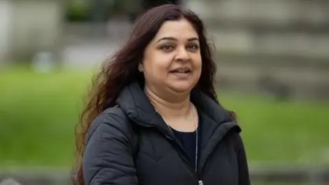 Tanya Nasir, who is wearing a black coat and top