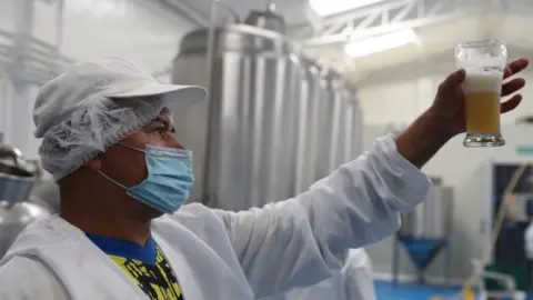 man looking at beer in brewery