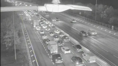 A black and white image shows lots of vehicles in three or four lanes on a motorway