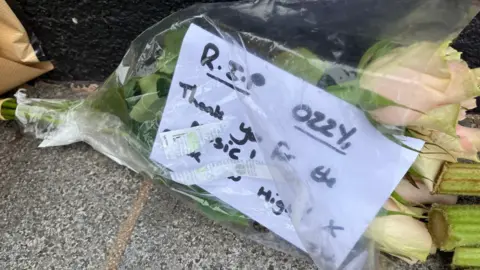 A card by flowers includes "R.I.P Ozzy, Thank you for the music"